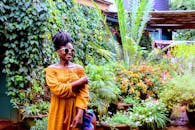 Photo of a Woman in Yellow Dress Standing Near Plants